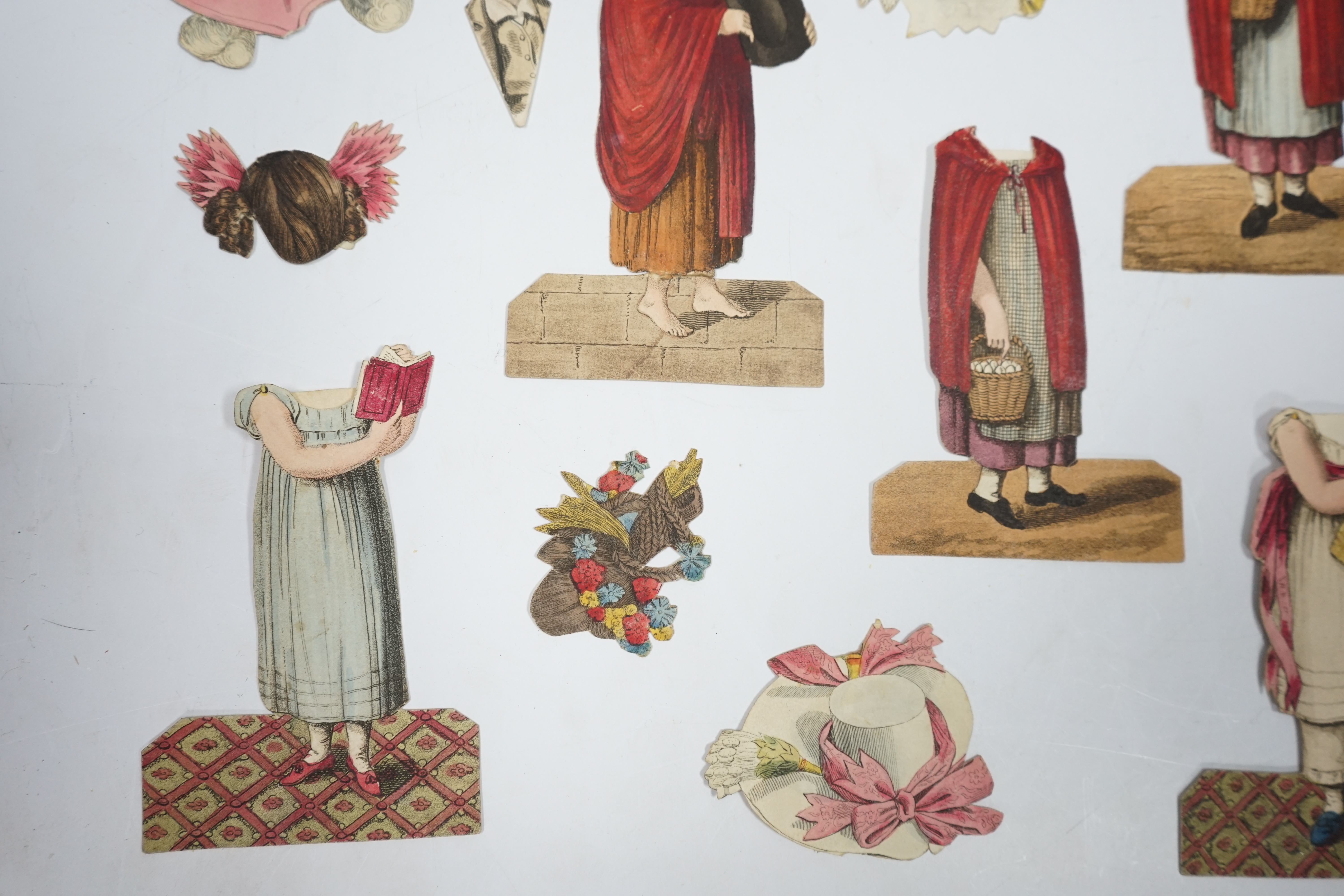 An early 19th century boxed Rudolph Ackermann La Poupee-Modele paper doll set, comprising of a double sided doll in lingerie with mahogany stand, six double sided gowns and four bonnets, together with eight similar figur